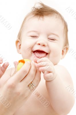 laughing baby boy in mother hands with rubber duck