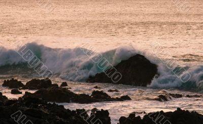 Crashing waves on rock in sunset