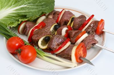 Appetizing shish kebab with vegetables and greens