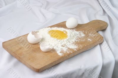 Eggs and a flour on a board