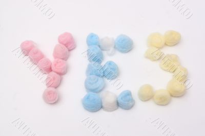 Word `yes` with blue, yellow and pink hygienic cotton balls