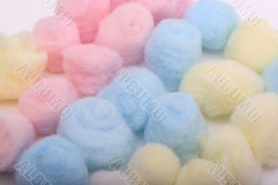 Yellow, blue and pink hygienic cotton balls in rows