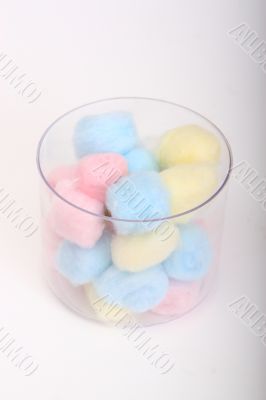 Blue and pink hygienic cotton balls in a glass canister