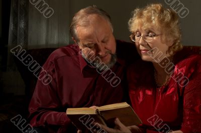 Happy elderly spouses behind reading