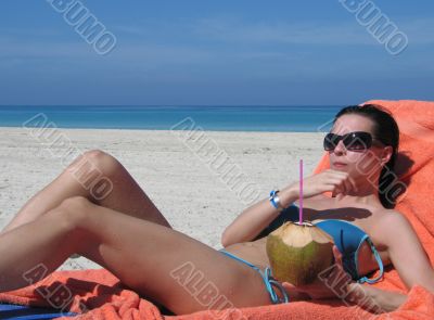 girl tanning and drinking out of a coconut