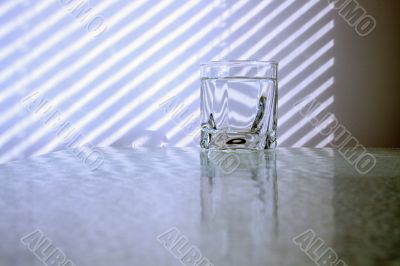 Glass of water and jalousie shadow