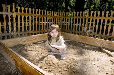 Child girl plaing at wood sand-box in summer park Child girl plaing at wood sand-box in summer park