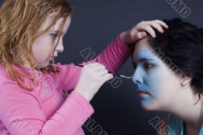 young girl is painting females face
