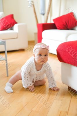 Happy baby girl crawling on a hardwood floor