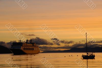 Big passenger ship and yacht at sunrise.
