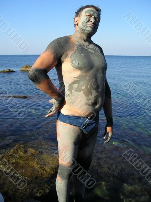 Man, smeared by therapeutic mud at sea