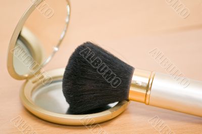Brush for makeup reflected in mirror on wooden table Brush for makeup reflected in mirror on wooden table