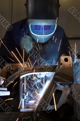 Welder welding a metal part in an industrial environment