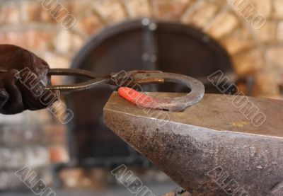 One horseshoe in pincers and an anvil