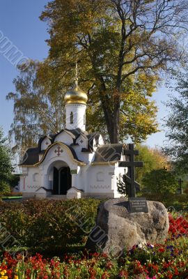 Small chapel among flowers and fall golden trees