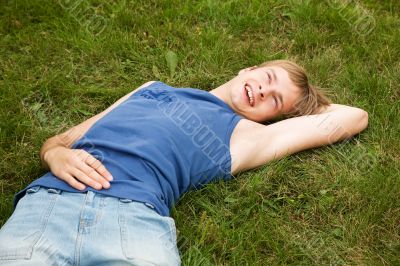 Smiling boy lying on the green grass Smiling boy lying on the green grass