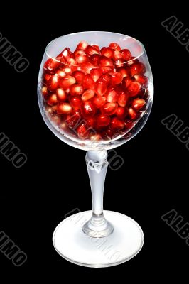 Pomegranate grains in a glass. Isolated on black. Pomegranate grains in a glass. Isolated on black.