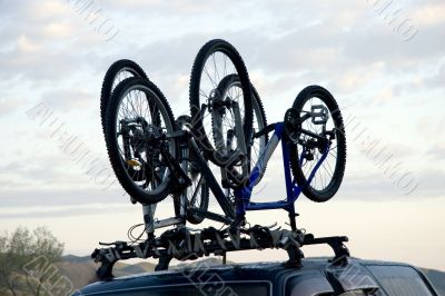 Three sports bicycles over jeep at sunrise in trip