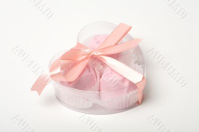 Little pink cakes in a heart shaped box over white