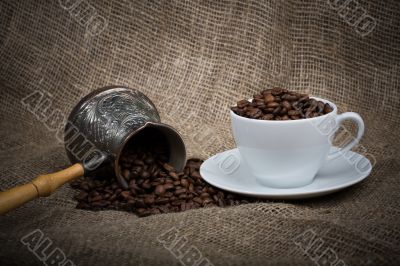 Cezve and cup with freshly roasted coffee beans on sackcloth