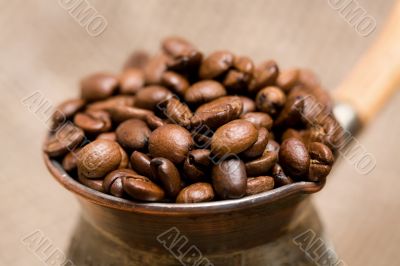 Cezve with freshly roasted coffee beans on sackcloth