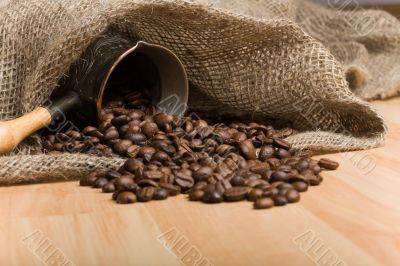 Sackcloth bag with cezve and roasted coffee beans on table Sackcloth bag with cezve and roasted coffee beans on table