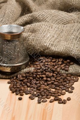 Cezve with freshly roasted coffee beans on table