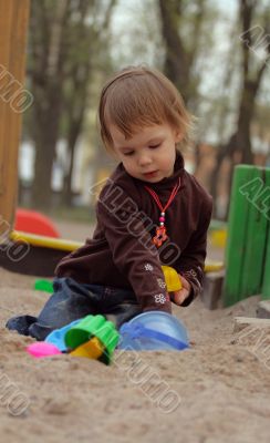 Little beauty girl playing at sand-box
