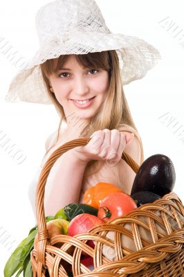An attractive young woman holding a basket of delicious fresh vegetables. Isolated on white.