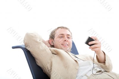 Young man rest in chair and listens digital player