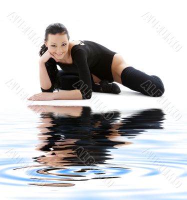 sporty girl in black leotard on white sand