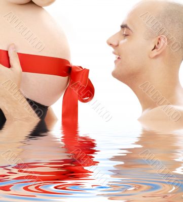 proud father and belly with red ribbon in water