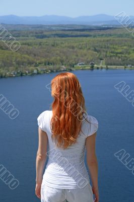 Red-haired girl looking over blue lake