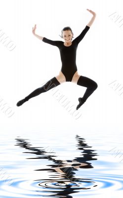 girl in black leotard jumping over water