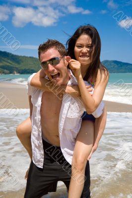 playful couple at the beach pulling ears