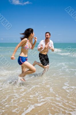 couple racing on the beach with joy