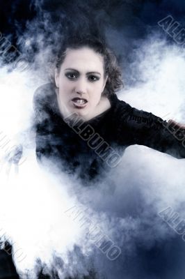 Woman with long curly hair crawling out of smoke
