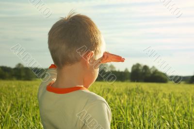 happy young boy looking horizon and dreaming on green field