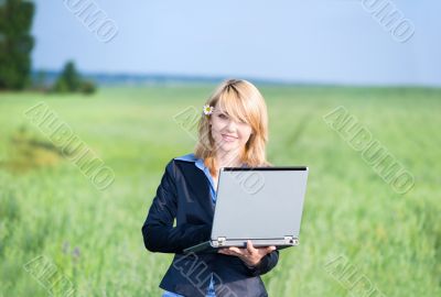 Girl with laptop stay on meadow at the noon