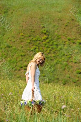 Sexy girl walk away with basket on a meadow