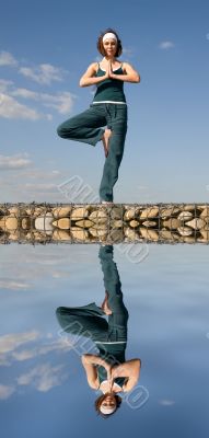 A woman doing yoga on a stone above  water