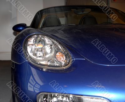Headlight of the dark blue sports automobile.