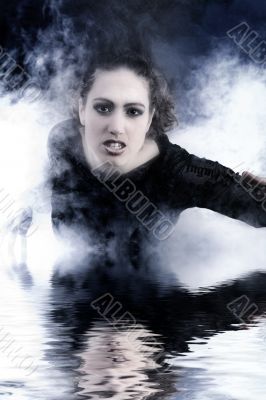 Woman with long curly hair crawling out of smoke Woman with long curly hair crawling out of smoke