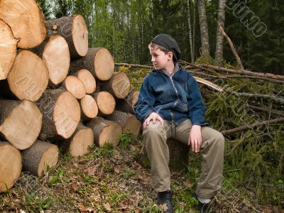 boy sitting near the prepared logs