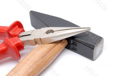 Hammer and flat-nose pliers with red handles isolated over white background