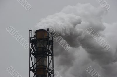 Smoking industrial pipe on gray sky