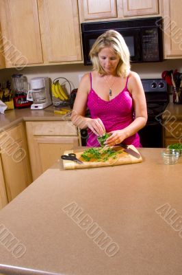 Blond woman cutting food in kitchen