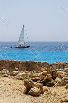 Stones on beach and yacht in sea