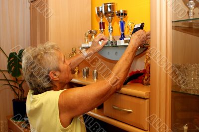 Old woman cleans their trophies. Old woman cleans their trophies.