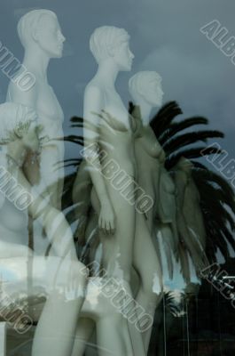 Mannequins in shop with reflection of palm tree